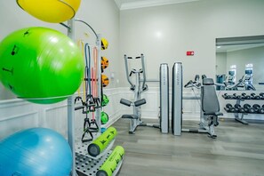 A gym with exercise equipment, including a green and blue exercise ball, a weight bench, and various machines. - Orlando at Your Doorstep, 3BR condo, Sleeps 8 (Orlando)