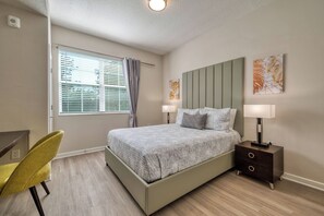 A bedroom with a bed, bedside lamps, a chair, a desk, and artwork on the wall. - Orlando at Your Doorstep, 3BR condo, Sleeps 8 (Orlando)