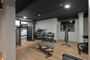 Un gimnasio con una banca, mancuernas y equipamiento de ejercicio.