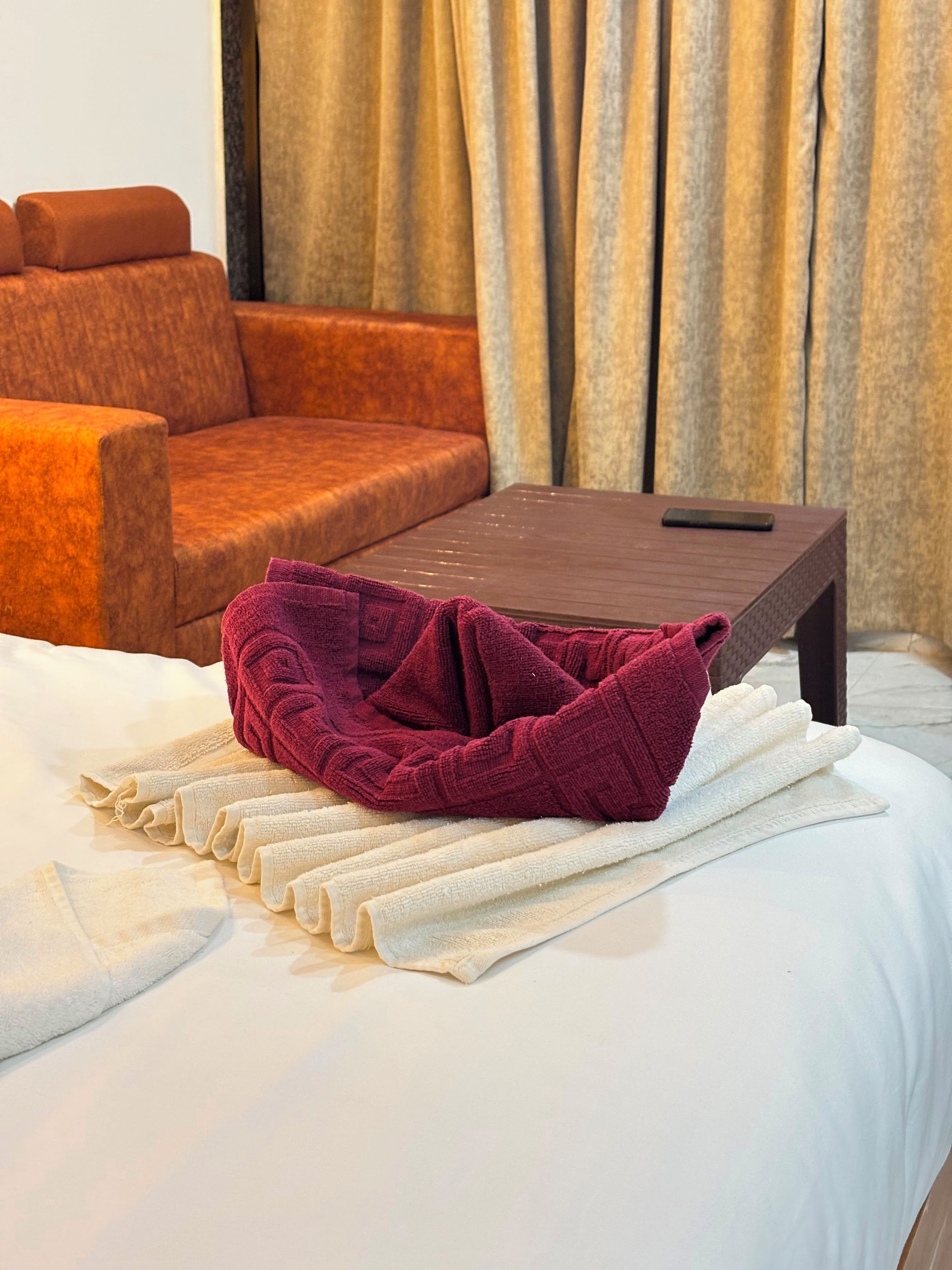 A bed with a white comforter and a folded red towel.