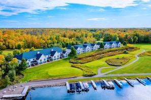 A large resort with multiple buildings, a golf course, and a marina with boats. - Izatys Hotel (Onamia)