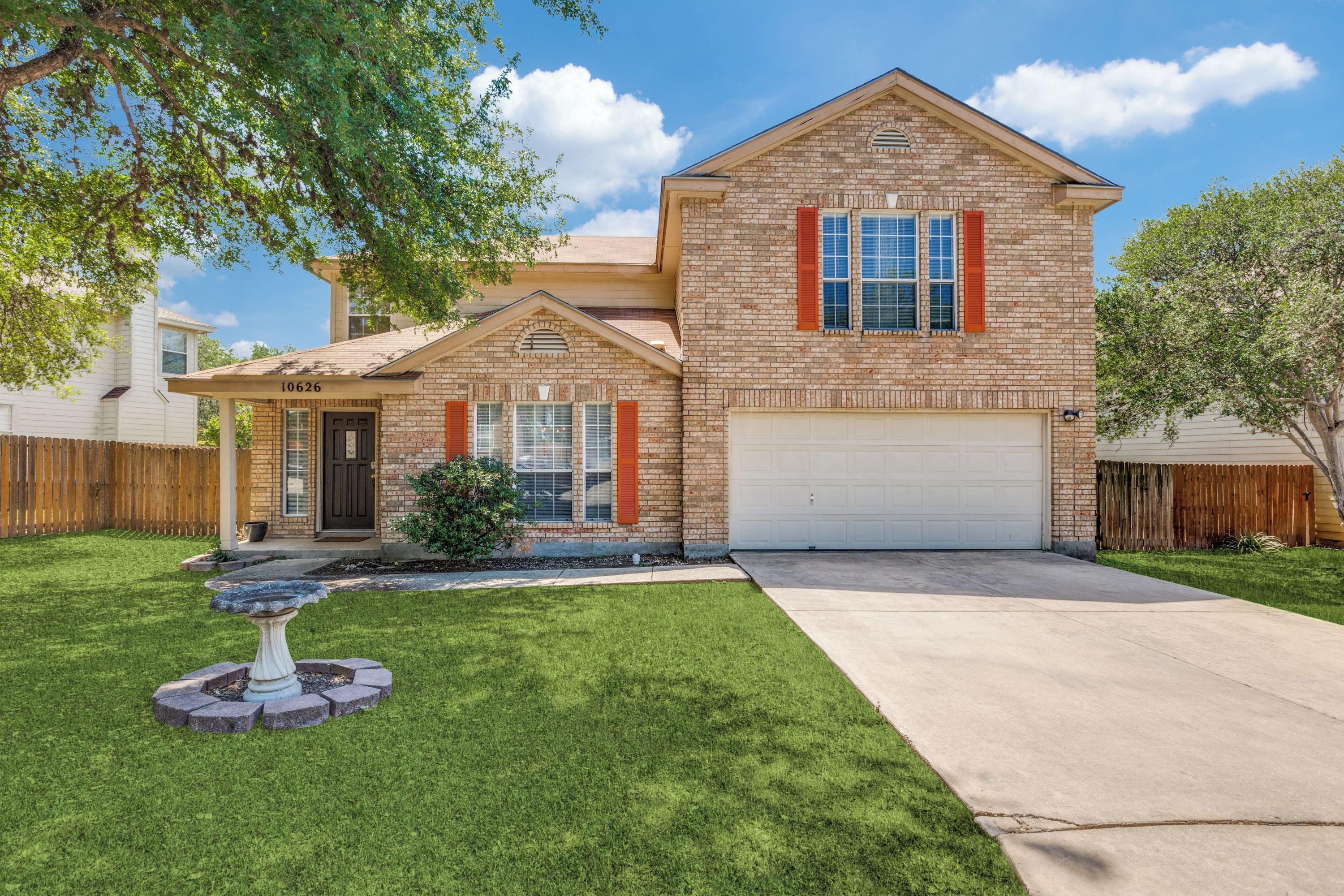A two-story house with a brick facade, a front porch, and a garage.