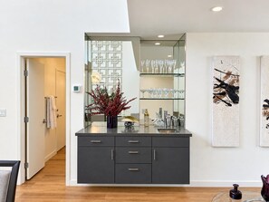 A modern bathroom with a dark grey vanity, a glass shower enclosure, and a large mirror. - Cozy 2 bedroom condo in south Palm Desert/ minutes from EL PASEO (Palm Desert)