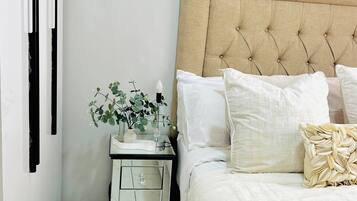 Un dormitorio ordenado con cama, mesita de noche y una planta en maceta.