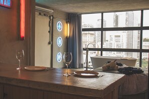 A bar area with a city view, a neon sign, and a window with curtains. - Romantic Studio at Mirante do Vale | Bathtub + 120" Cinema @cheng.du11 (São Paulo)