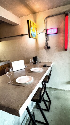A dining area with a long table, chairs, a neon sign, and a laptop. - Romantic Studio at Mirante do Vale | Bathtub + 120" Cinema @cheng.du11 (São Paulo)