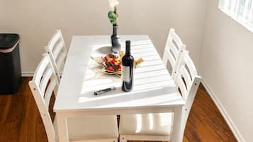 A dining table with chairs, a vase with flowers, a bottle, and a decorative item.