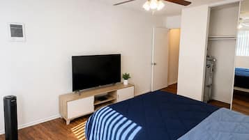 A bedroom with a bed, a television, a ceiling fan, and a wardrobe.