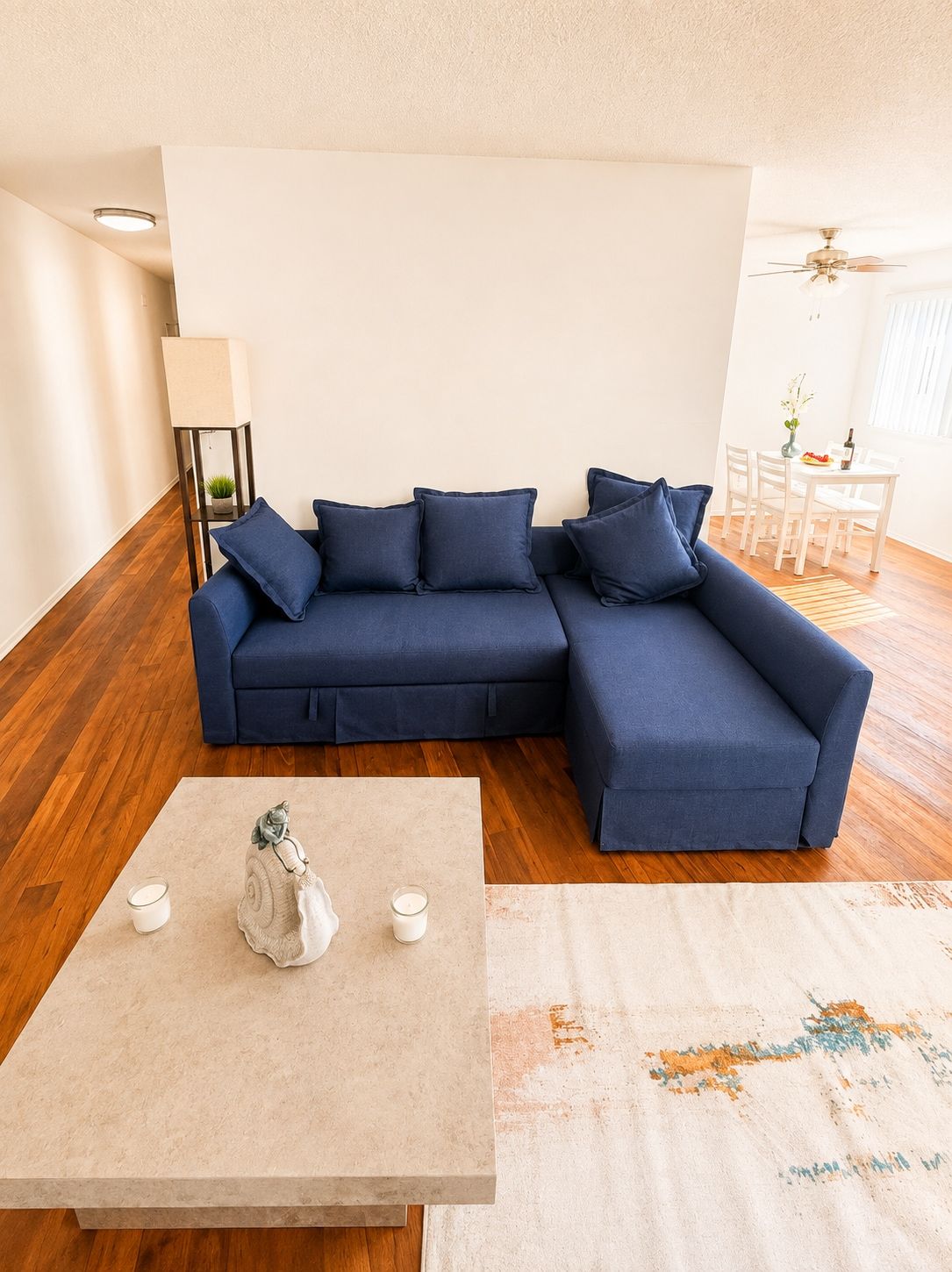 A modern living room with a blue sectional sofa, a small table with candles, and a decorative item.