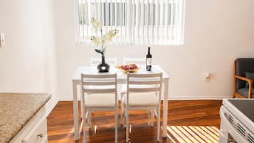 A kitchen with a dining table, chairs, a ceiling fan, a window with blinds, and a countertop.