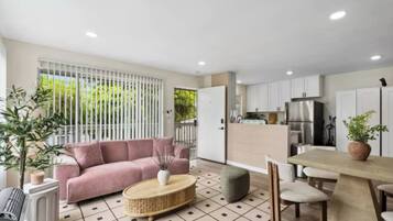 A modern living space with a sofa, a dining table, and a kitchen area.