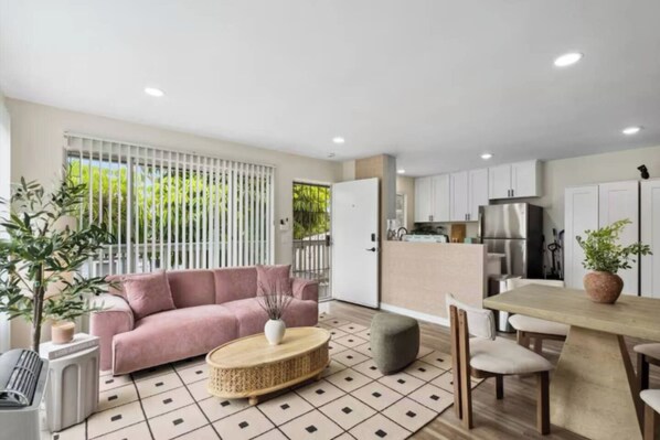 A modern living space with a sofa, a dining table, and a kitchen area. - Pacific Beach 5BR Getaway | 2 Units, Near Beach (San Diego)
