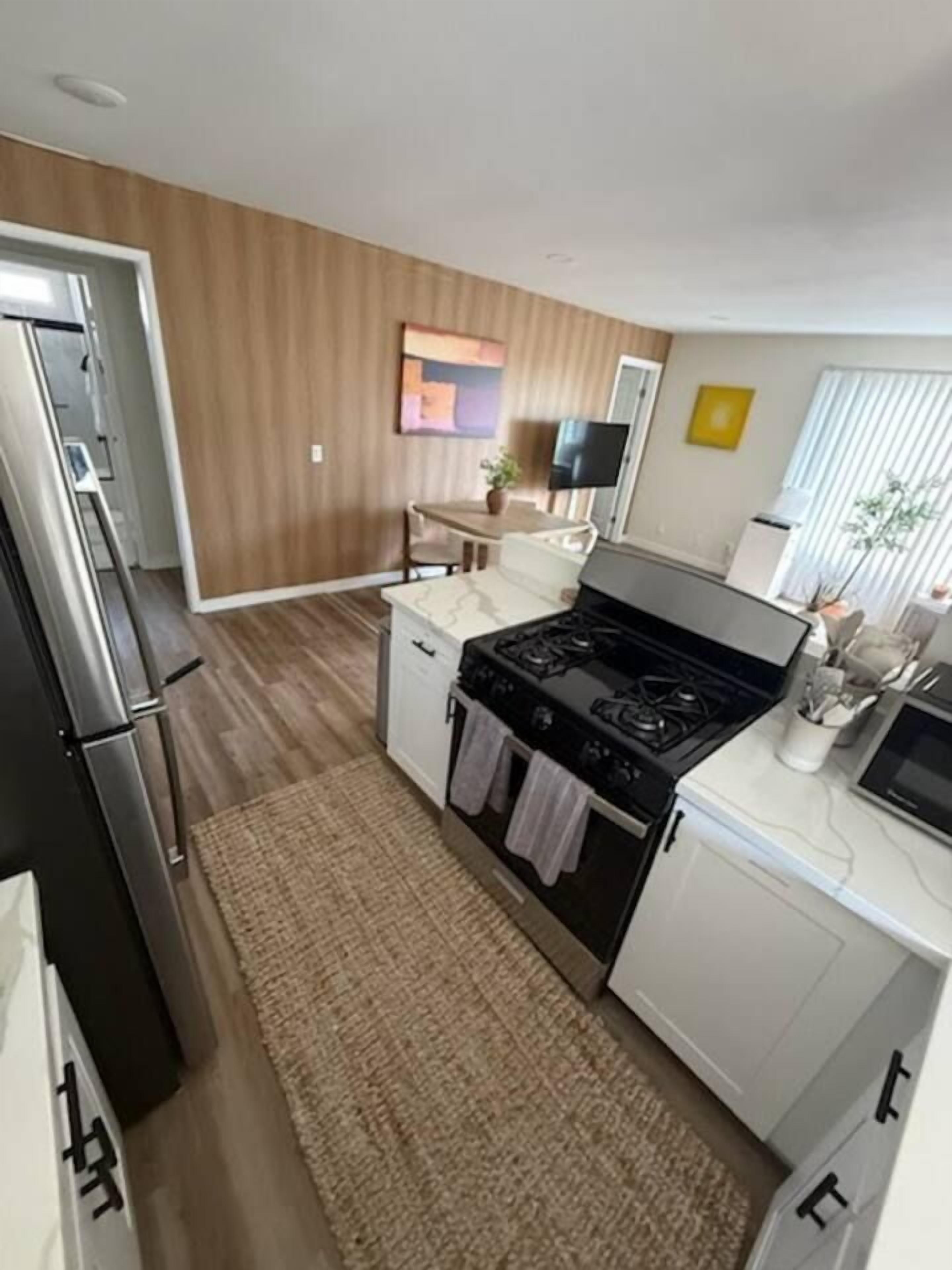 A compact kitchen with a stove, refrigerator, and white cabinetry.