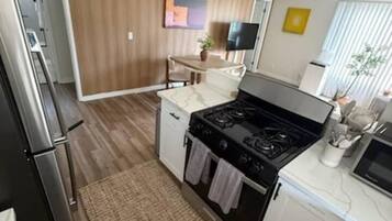 A compact kitchen with a stove, refrigerator, and white cabinetry.
