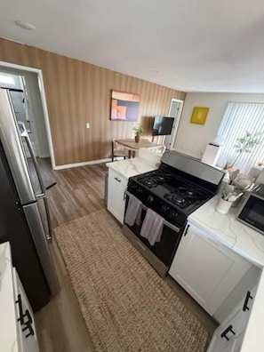 A compact kitchen with a stove, refrigerator, and white cabinetry. - Pacific Beach 5BR Getaway | 2 Units, Near Beach (San Diego)