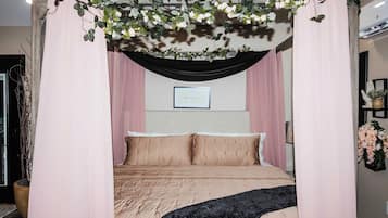 A bedroom with a canopy bed, a framed message on the wall, and a potted plant.