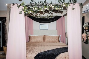 Ein Schlafzimmer mit Baldachinbett, einer gerahmten Nachricht an der Wand und einer Topfpflanze.