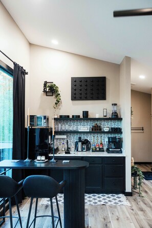 A modern kitchen with a bar area, featuring a coffee machine, a microwave, and a toaster.