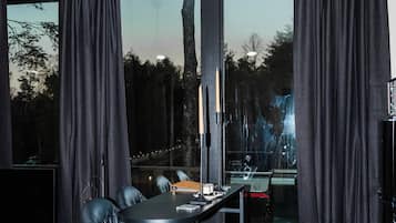 Un salon moderne avec un canapé noir, une petite table ronde et un téléviseur.