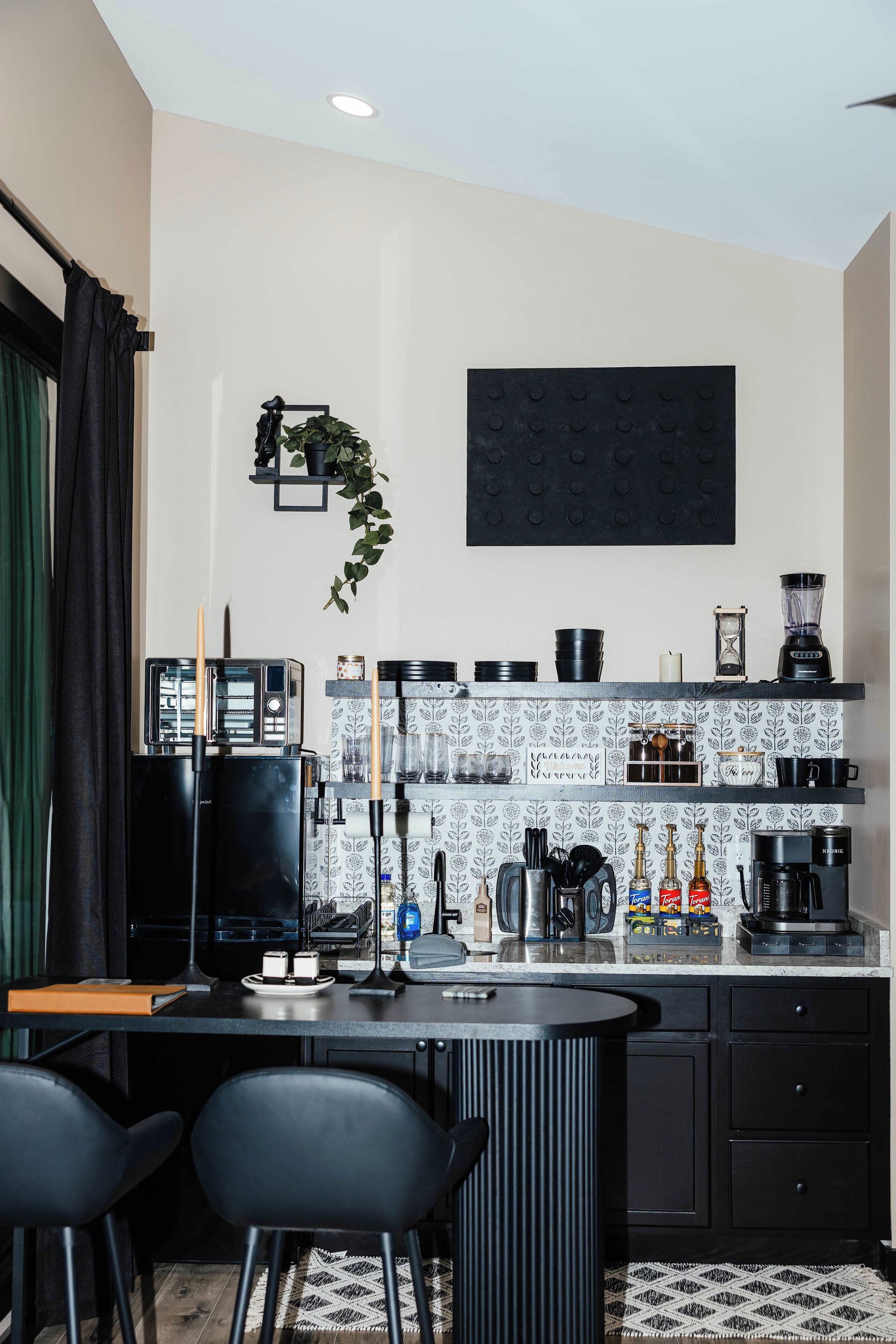 A modern kitchen with black appliances, a coffee machine, and a bar area with stools.