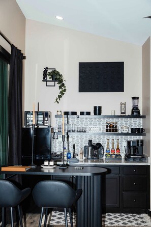 A modern kitchen with black appliances, a coffee machine, and a bar area with stools.
