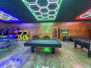 A recreational room with a pool table, foosball table, and arcade games.