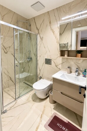 Un bagno moderno con cabina doccia in vetro, un water e un lavandino con specchio sopra.