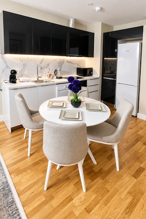 Una cucina moderna con zona pranzo, caratterizzata da un tavolo rotondo con sedie, un frigorifero e un forno a microonde.