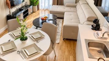 A modern living room with a sofa, dining table, and a flat-screen TV.