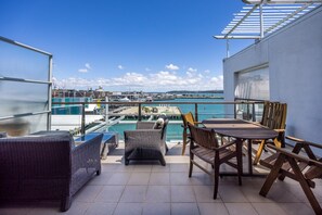 A terrace with a view of a marina, outdoor furniture, and a clear sky. - Dual-Level Harbour Apartment on The Wharf (Auckland City)