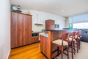 Eine moderne Küche mit Holzschränken, einer Mikrowelle und einer Bar mit Sitzgelegenheiten.