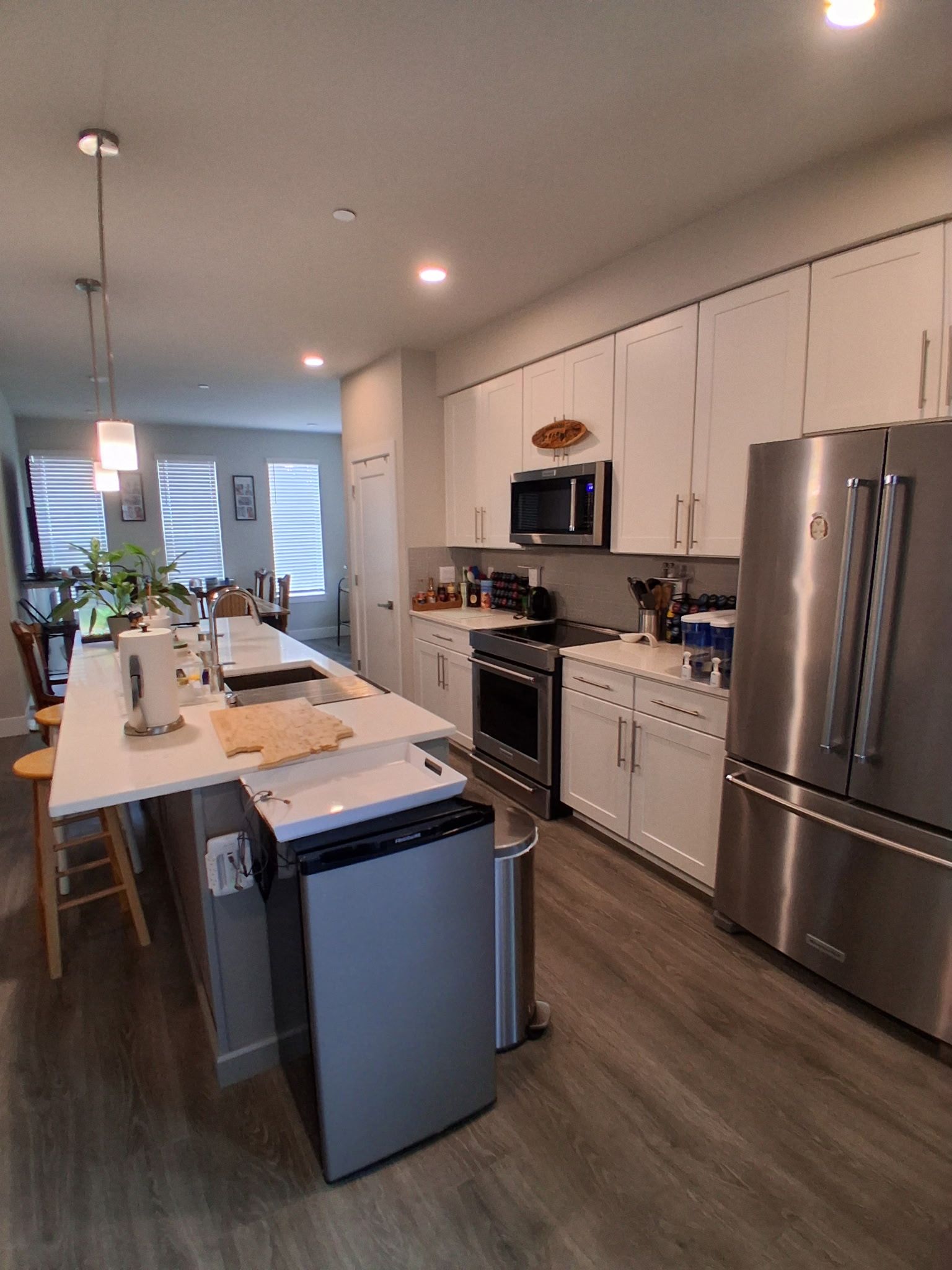 A modern kitchen with stainless steel appliances, a central island, and a dining area with a view.