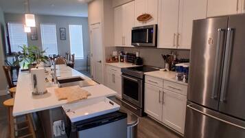 A modern kitchen with stainless steel appliances, a central island, and a dining area with a view.