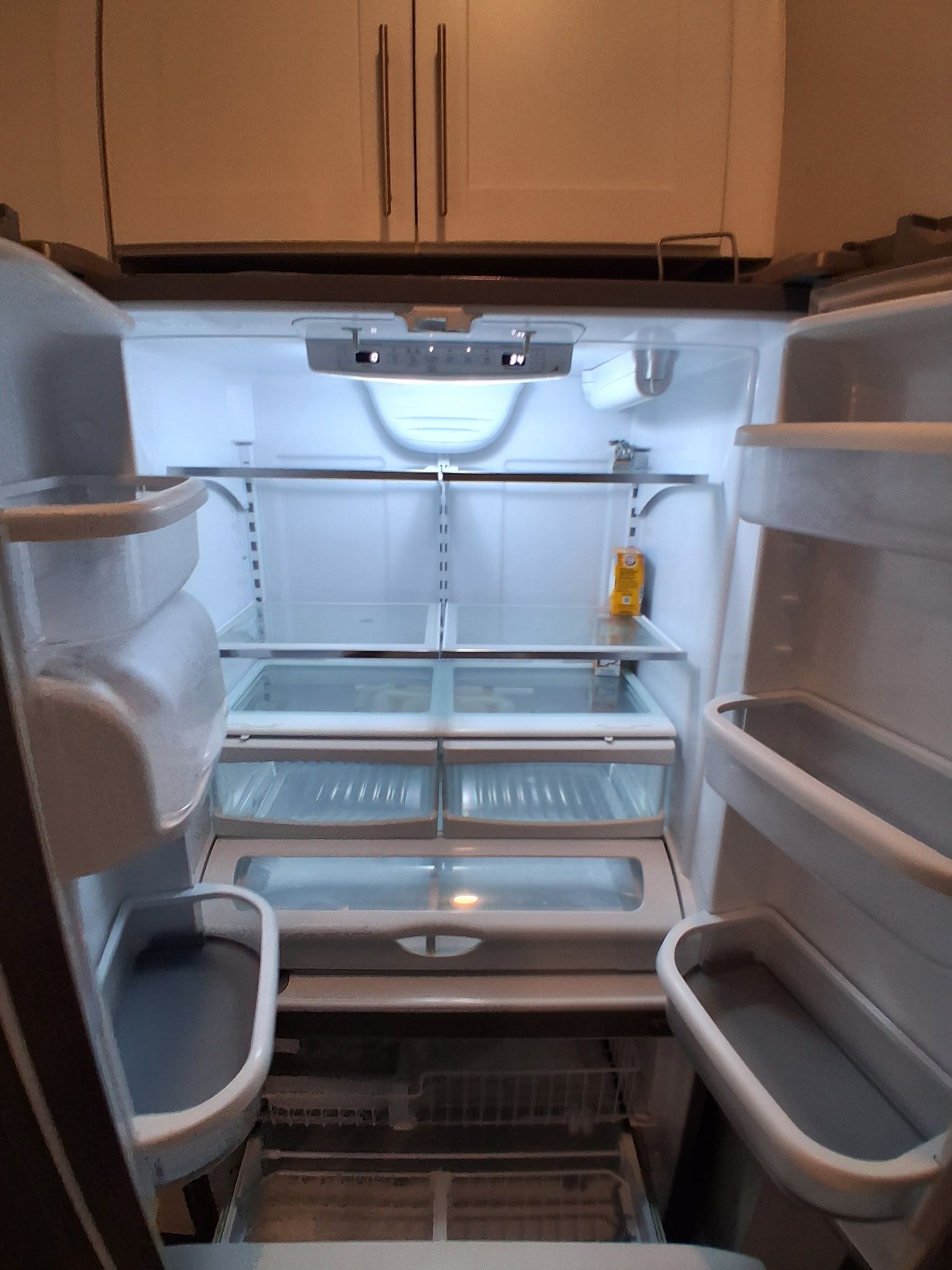 An interior of a refrigerator with multiple shelves and a freezer compartment.