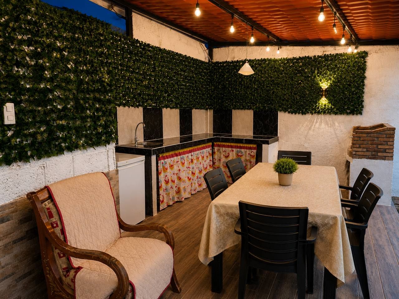 Un comedor acogedor con una mesa dispuesta para cuatro personas, rodeada de sillas. Hay una pequeña planta en maceta sobre la mesa, y el espacio tiene un techo de madera rústica.