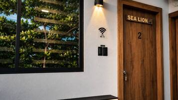 A hotel room with a large window, a wall-mounted Wi-Fi sign, and a door labeled 'SEA LION 2'.