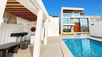 Una casa moderna con piscina, una zona relax coperta e una grande finestra con vista sulla piscina.