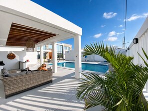 Un espace extérieur moderne, aménagé avec des sièges, une piscine, des murs blancs et un ciel dégagé.