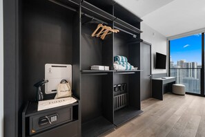 Ein modernes Hotelzimmer mit begehbarem Kleiderschrank, Fön, Aufbewahrungsbox und Blick auf die Stadt.