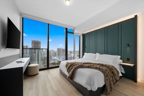 Un dormitorio moderno con una cama grande, un escritorio y vistas a la ciudad.
