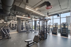 A gym with various exercise equipment, large windows, and a high ceiling. - Luxury 27th Floor Suite E11EVEN w/ Rooftop Pool (Miami)