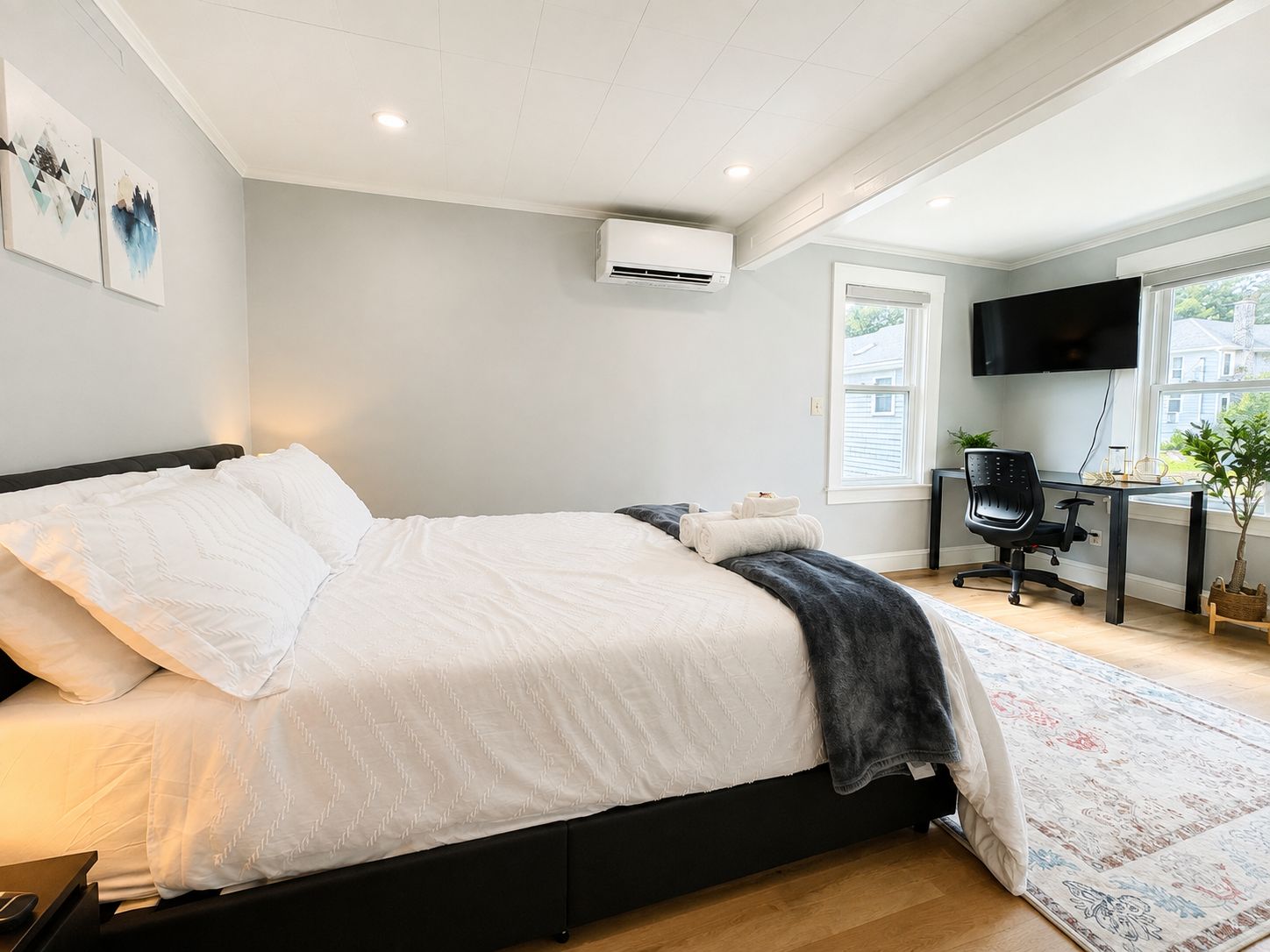 Une chambre à coucher moderne, équipée d’un lit, d’un bureau, d’une chaise et d’un téléviseur.