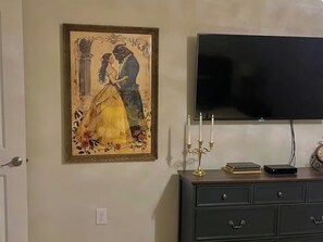 A framed painting of a couple, a television, and a candelabra on a dresser. - Spacious 5-BR Disney themed townhome in Davenport, Windsor Island Resort (Davenport)
