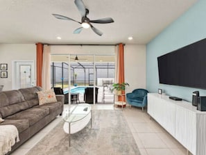 A modern living room with a sofa, coffee table, and a TV. - Spacious 5-BR Disney themed townhome in Davenport, Windsor Island Resort (Davenport)