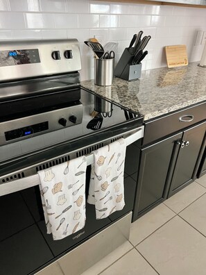 A kitchen with a stainless steel stove, a digital clock, and a knife block on the countertop. - Spacious 5-BR Disney themed townhome in Davenport, Windsor Island Resort (Davenport)