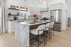 A modern kitchen with a large island, stainless steel appliances, and bar stools. - Brand New Modern Home, Steps to Bottleworks! (Indianapolis)