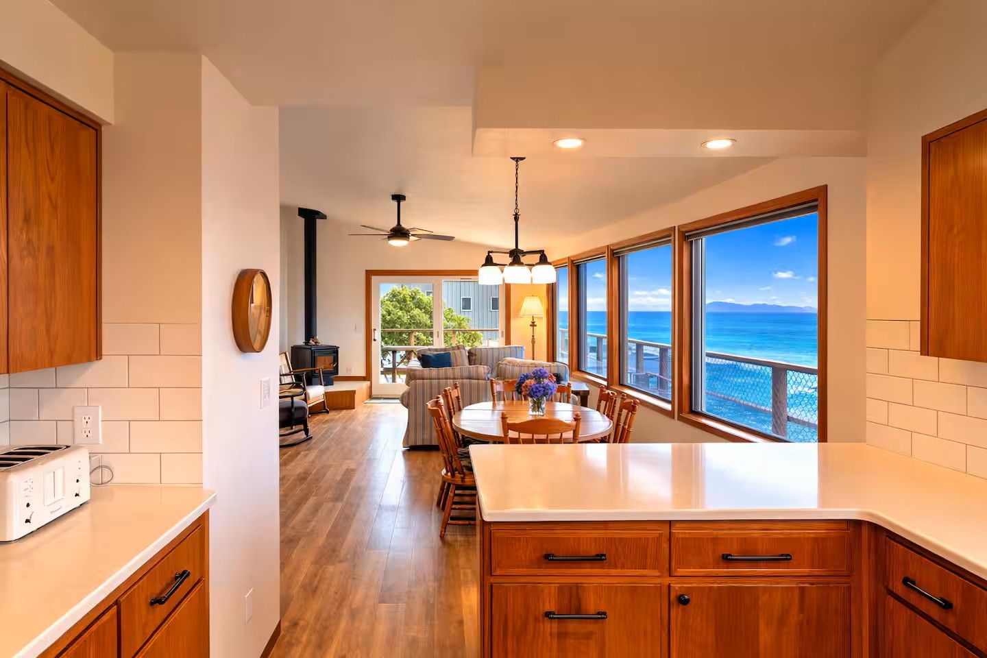 Una cocina moderna con armarios de madera, una isla central y grandes ventanas con vista al océano.