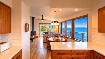 Una cocina moderna con armarios de madera, una isla central y grandes ventanas con vista al océano.