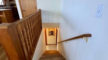 A wooden staircase with a handrail, leading to a landing with a framed picture.