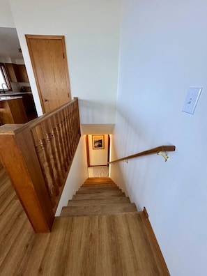 A wooden staircase with a handrail, leading to a landing with a framed picture.